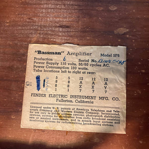 1957 Fender Bassman 5F6 Narrow Panel 40-Watt 4x10" Guitar Combo by Fender, featuring a rectangular label with serial number, warranty info, and tube layout chart on wood; handwritten marks add character.