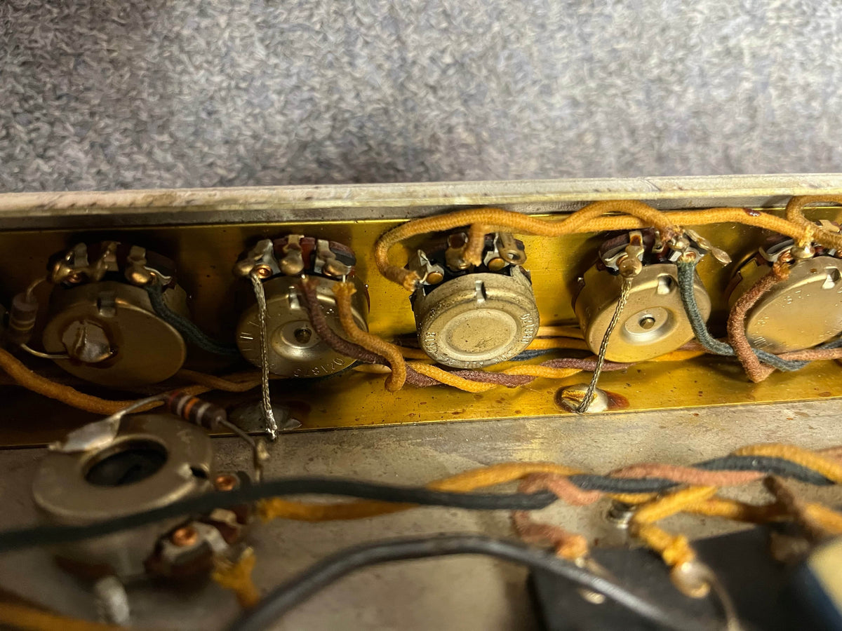 Close-up of four vintage potentiometers with wiring inside a 1966 Fender Black Panel Twin Reverb 2-Channel 85-Watt 2x12" Guitar Combo Amp w/Case, possibly part of its classic spring reverb circuitry, against a textured background.