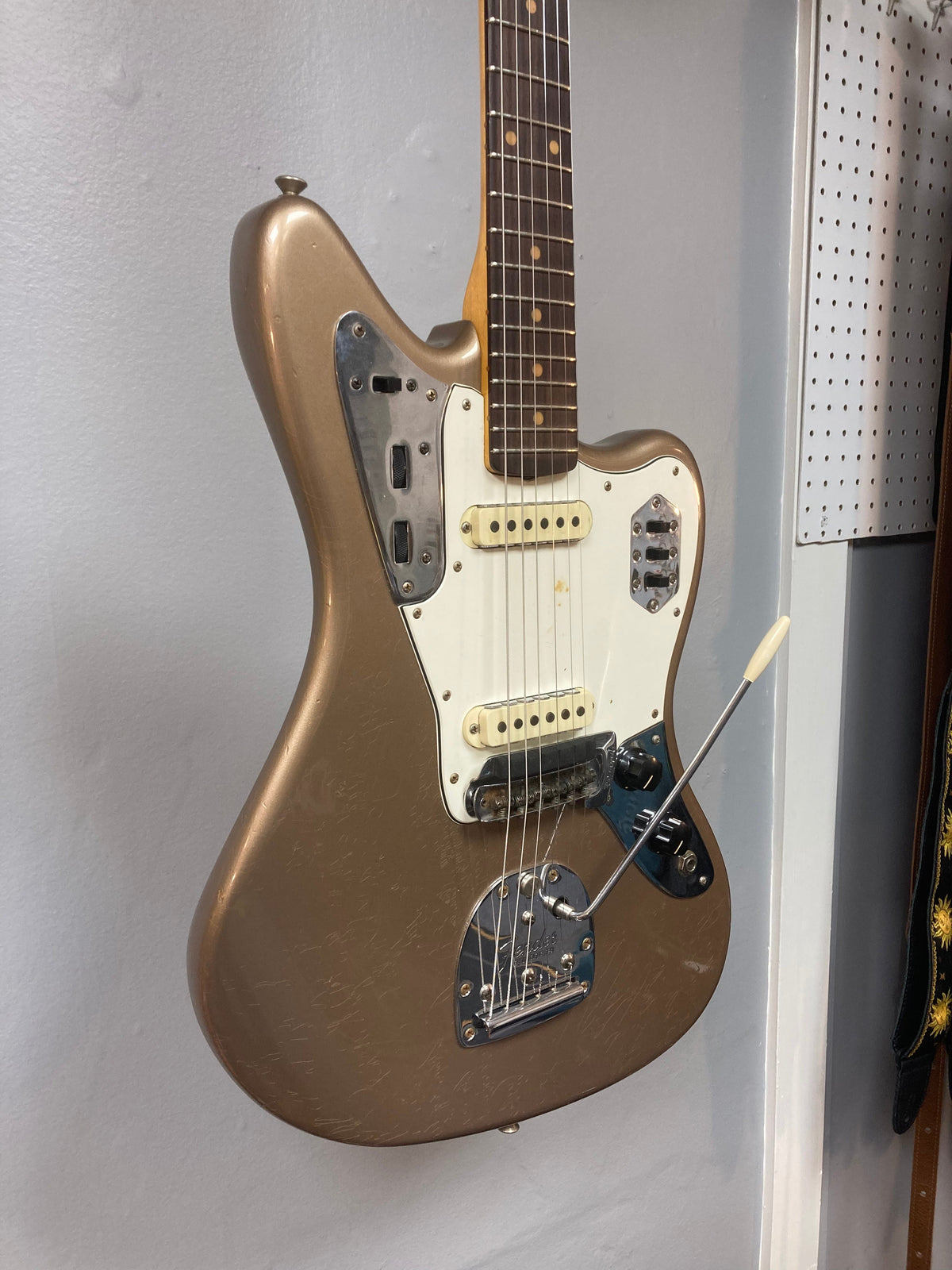 Fender Custom Shop Jaguar Journeyman electric guitar with white and black hardware, displayed on a wall.