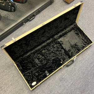 A beige rectangular guitar case with black plush lining sits on a gray carpet, ready to hold your prized Fender 2006 Eric Johnson Stratocaster or any signature guitar.
