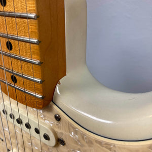 Close-up of the 2006 Fender Eric Johnson Stratocaster by Fender, highlighting its maple fingerboard, metal frets, cream body, and a portion of the white pickguard on this signature guitar.