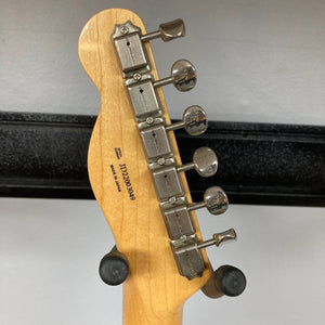 Close-up of the back of a Fender Heritage '60s Telecaster Custom Made in Japan Sunburst headstock, showing six metal tuners and visible serial number, resting on a stand—classic vintage style from Fender.