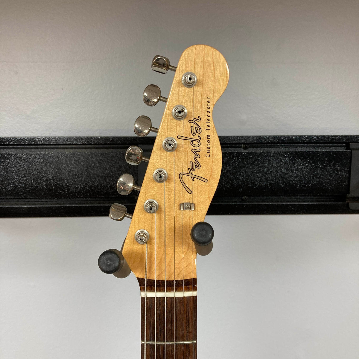 Headstock of a Fender Heritage '60s Telecaster Custom Made in Japan Sunburst w/Gigbag Consign by Fender, featuring six tuning pegs, displayed on a wall hanger against a white background.