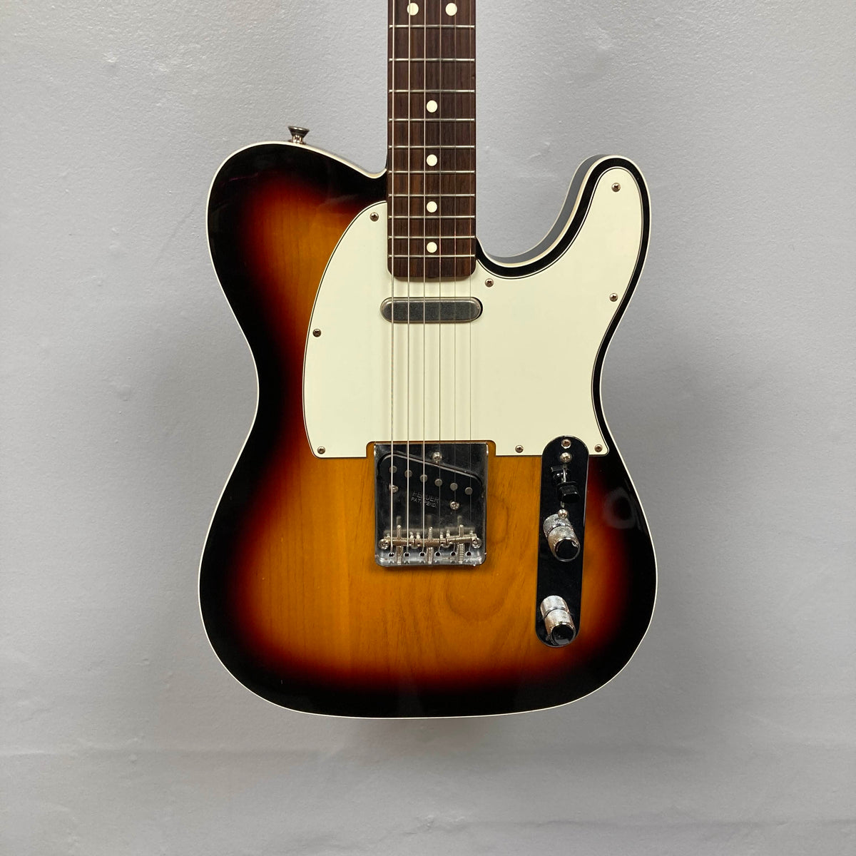 A Fender Heritage '60s Telecaster Custom Made in Japan Sunburst electric guitar with a white pickguard and two control knobs is displayed against a plain light gray background. Comes with gigbag; consign item.
