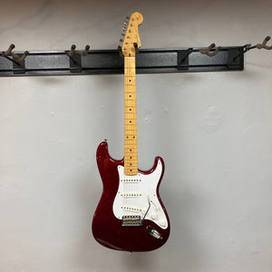 Fender Japan Stratocaster Candy Apple Red 2004 w/Case on a wall hook.