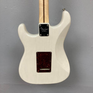A rear view of the Fender Limited Edition Ash American Professional Stratocaster White Blonde w/Case Consign shows its neck joint, backplate, and tremolo cavity cover against a light gray wall.
