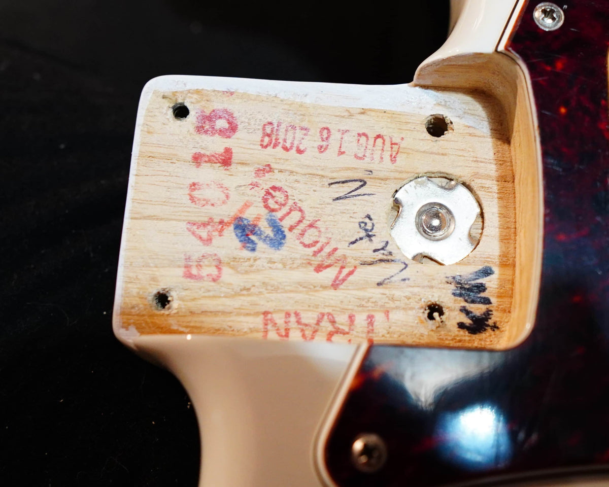 Close-up of a Fender Limited Edition Ash American Professional Stratocaster White Blonde guitar neck pocket showing wood grain, screws, metal insert, serial numbers, manufacturer marks, and handwritten notes.