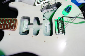 Close-up of a Fender Limited Edition Ash American Professional Stratocaster White Blonde body, showing exposed cavities, bridge, loose strings, visible pickup covers, and wiring; by Fender.