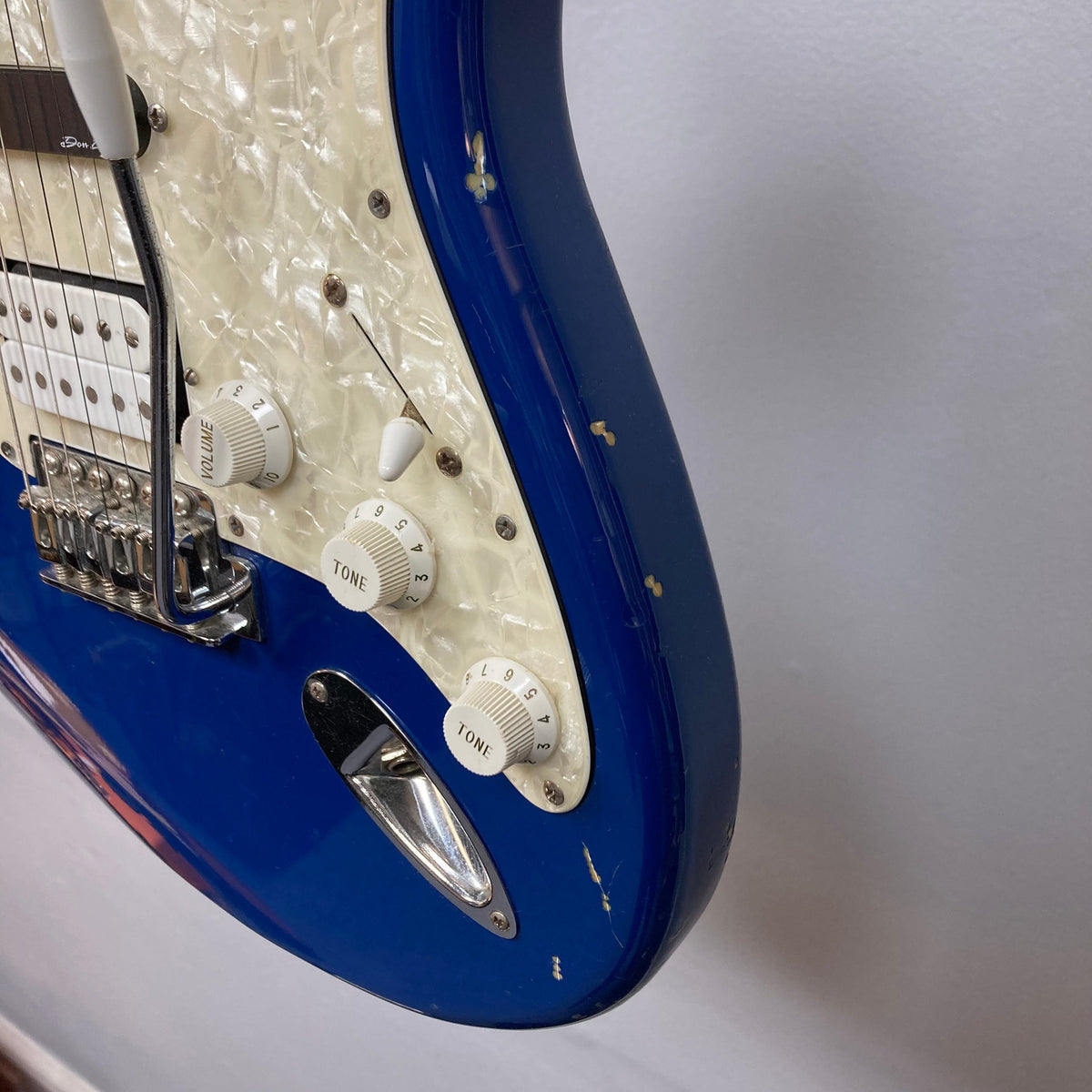 Close-up of a Fender MIM Stratocaster Blue 1998, showcasing its white volume knob, pickups, and classic design. Used condition with case included.