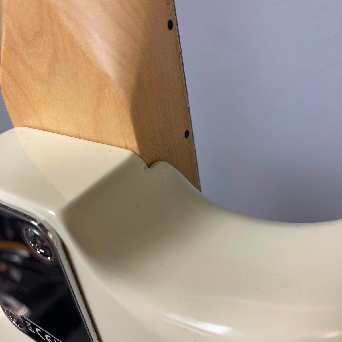 Close-up of the neck joint on a Fender Standard Stratocaster Olympic White Refurb by Fender, highlighting the connection between the neck and body just above its single coil pickups.