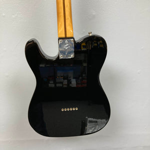 A Fender Vintera II ’60s Telecaster Thinline Black Used electric guitar by Fender is hanging on a white wall with its back facing the camera. Featuring a semi-hollow ash body and vintage-style Tele pickups, this classic guitar showcases both timeless design and rich tone.