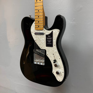 A Fender Vintera II ’60s Telecaster Thinline Black Used electric guitar with a semi-hollow ash body, white pearloid pickguard, maple neck, and vintage-style Tele pickups by Fender hangs on a light gray wall.