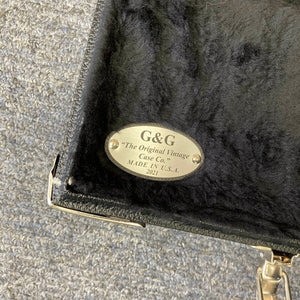 A metal label inside the black fur-lined case reads "G&G 'The Original Vintage Case Co.' MADE IN U.S.A. 2021." The G&L L-2000 USA Tobacco Sunburst Bass w/Case Used Consign sits on a textured gray surface.