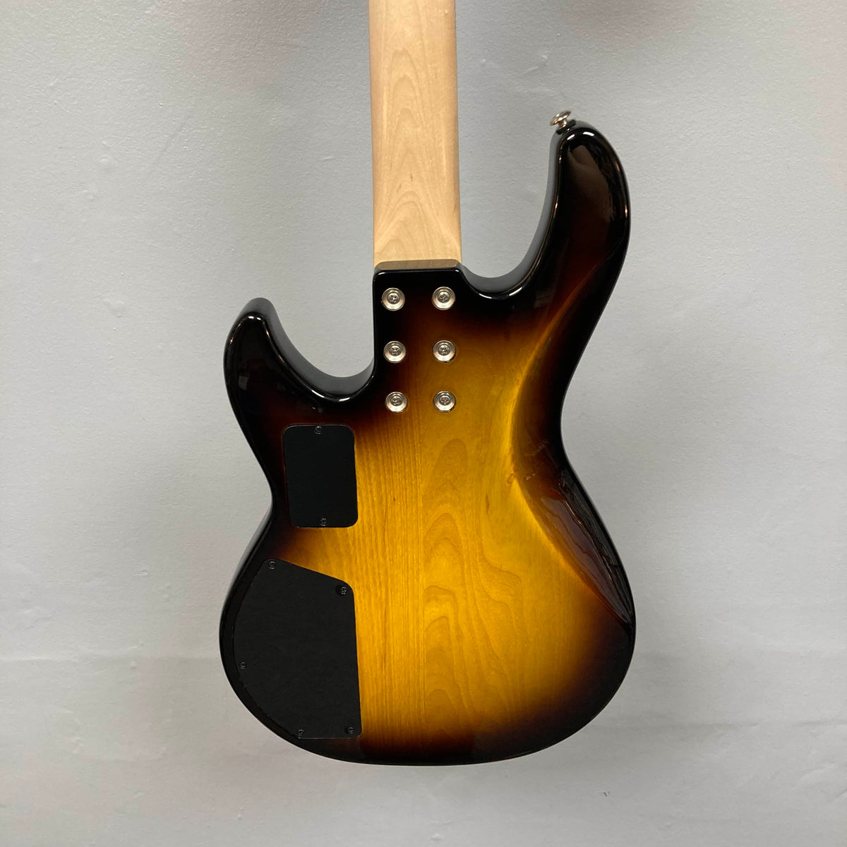 The back of the G&L L-2000 USA Tobacco Sunburst Bass w/Case (Used Consign) displays its neck joint, body contours, and two black access panels against a light gray wall.