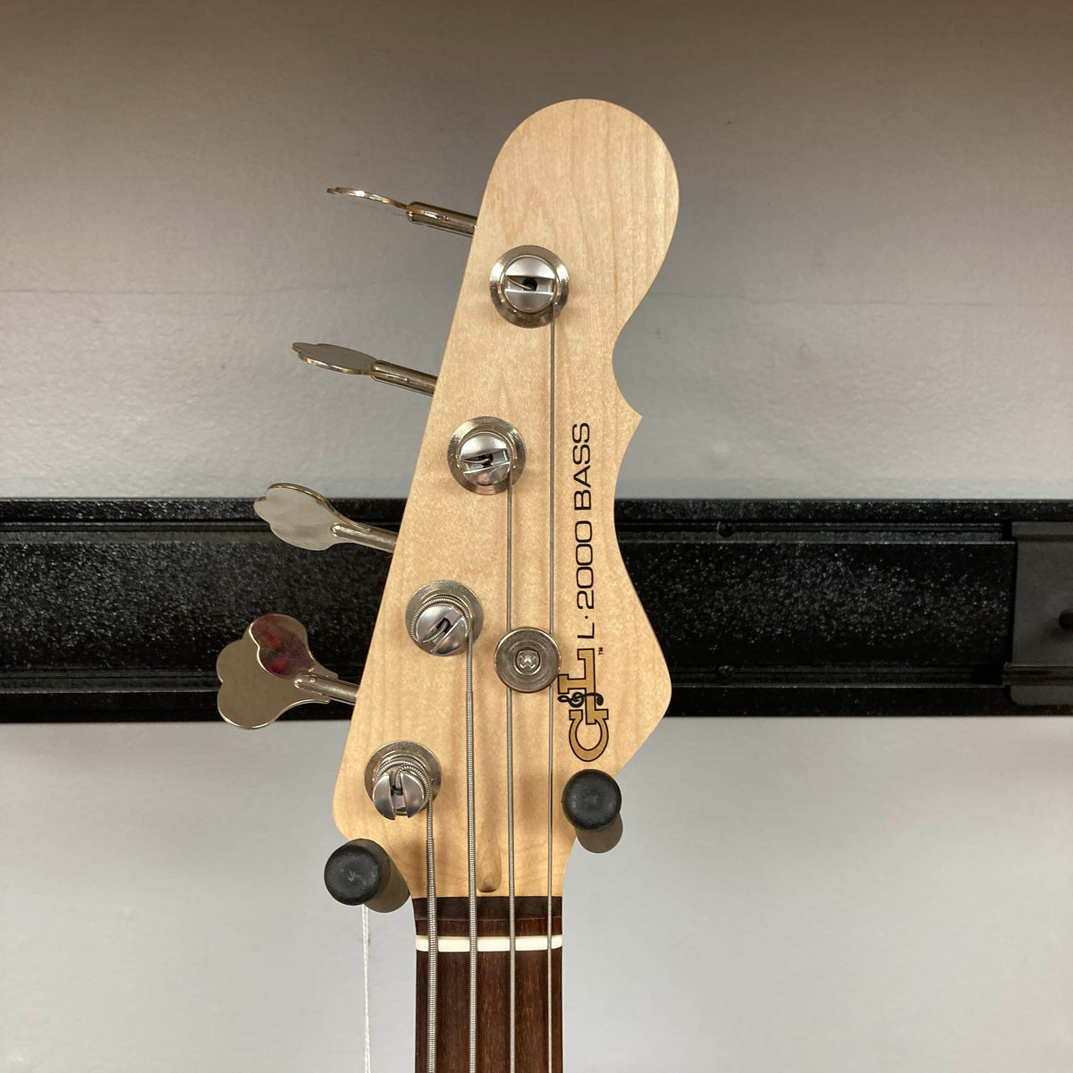 The headstock of the G&L L-2000 USA Tobacco Sunburst Bass w/Case Used Consign shows its tuning pegs, strings, and G&L logo against a plain background.