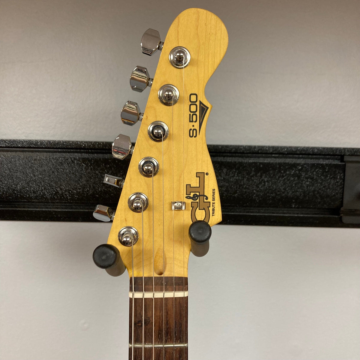 G&amp;L Tribute Series S-500 Irish Ale Used, close-up of guitar head with pegs on a stand, highlighting tuning hardware and craftsmanship.