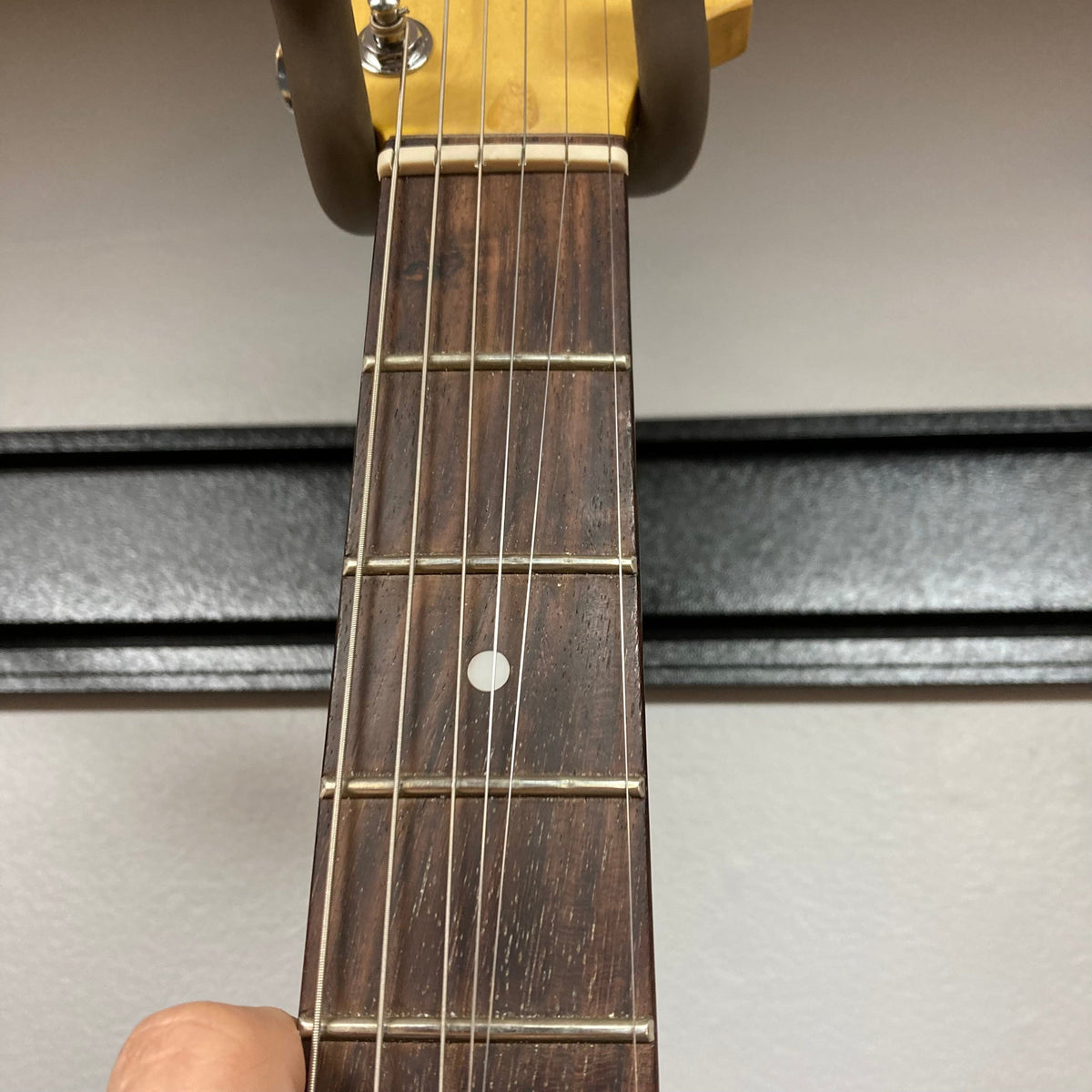 Hand holding the G&amp;L Tribute Series S-500 Irish Ale Used guitar, showcasing the guitar neck and strings in close-up.