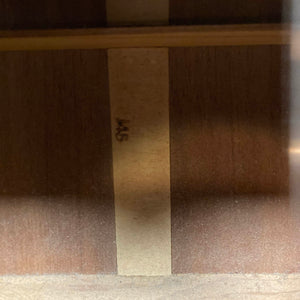Wooden surface with vertical strips and “145” on a lighter strip, echoing the timeless design of the Gibson J-45 1957 Serial U-8664-1 by Gibson—classic charm reimagined.