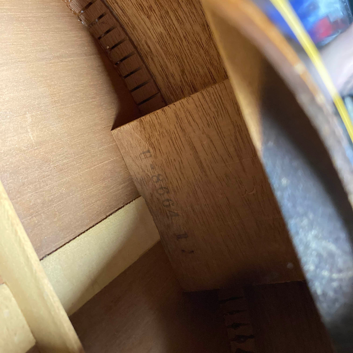 Close-up of the interior of a vintage Gibson J-45 1957 acoustic guitar, highlighting detailed wooden bracing and the stamped serial number "U-8664-1" on the inside.