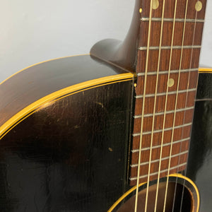 Close-up of a Gibson J-45 1957 (Serial U-8664-1) guitar, highlighting its slope shoulder body, aged finish with visible cracks and scratches, and yellowed binding.