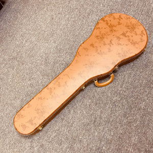 A brown hard-shell guitar case with a handle rests on a gray carpet—ideal for storing a Gibson Les Paul Junior 1957 Sunburst electric guitar by Gibson.