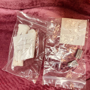 Two plastic bags on a pink surface—one with white cylindrical objects, the other with small metal cylinders—both are hand-labeled, likely vintage parts from a Gibson Les Paul Junior 1957 Sunburst electric guitar by Gibson.