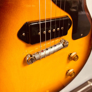 Close-up of a Gibson Les Paul Junior 1957 Sunburst body, highlighting its bridge, P-90 pickup, control knobs, and strings in classic Gibson style.