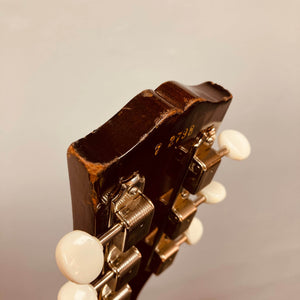 Close-up of the back of a Gibson Les Paul Junior 1957 Sunburst headstock, highlighting metal tuning pegs, white knobs, and a stamped serial number—classic features of this vintage Gibson electric guitar.
