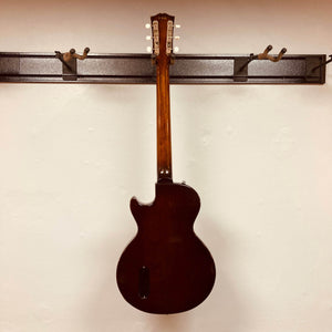 A Gibson Les Paul Junior 1957 Sunburst electric guitar by Gibson hangs by its neck on a wall rack, displayed with its back facing outward.
