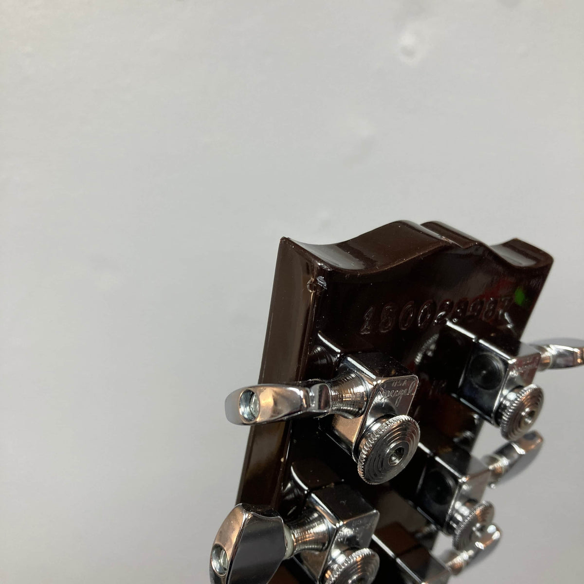 Close-up of the back of a Gibson Les Paul Studio 2015 Desert Burst headstock, featuring chrome locking tuners and visible serial number. Includes case.