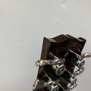 Close-up of the back of a Gibson Les Paul Studio 2015 Desert Burst headstock, featuring chrome locking tuners and visible serial number. Includes case.