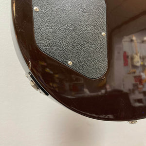 Close-up of the back of a Gibson Les Paul Studio 2015 Desert Burst, featuring a textured black plastic cover plate secured with screws.