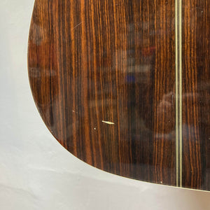 Close-up of the back of a Gibson Nouveau NV6-R 1986 acoustic guitar, highlighting its wood grain, vertical inlay stripe, and a visible scratch—signs of a well-played square-shoulder dreadnought from Gibson.