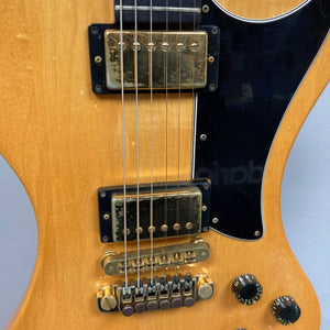 Close-up of a vintage Gibson RD Artist 1977-1982 from Guitars on Main, featuring dual humbucker pickups, bridge, control knobs, strings, and pickguard detail against a light wood finish; includes case.