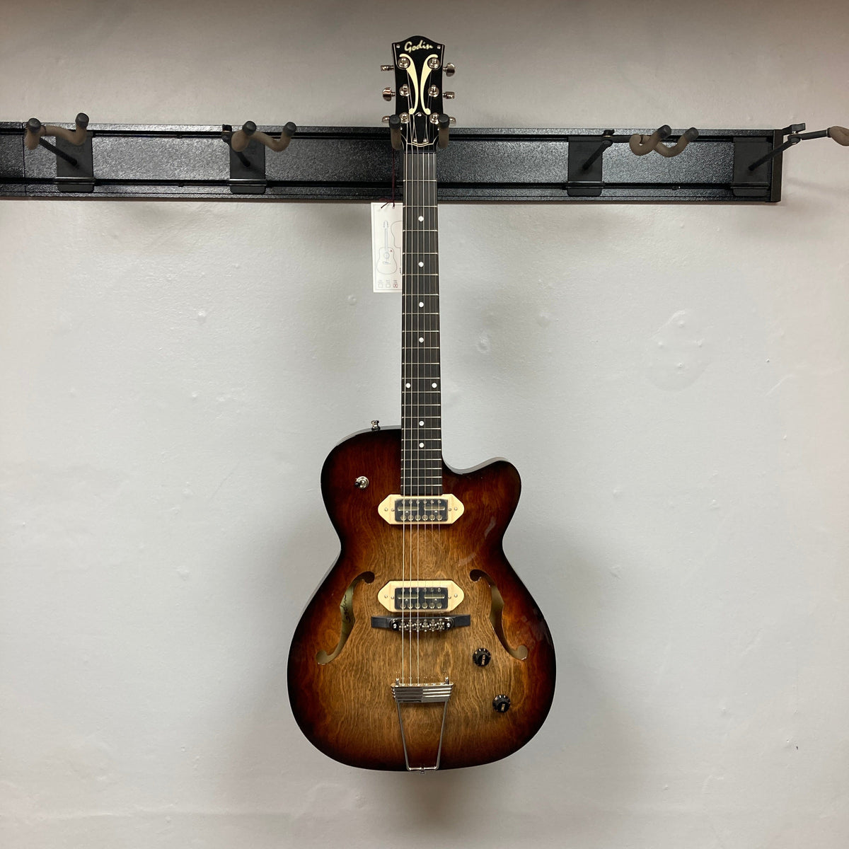 Godin 5th Ave TL Vintage Burst HG Gold Foil electric guitar, hollow-body design, mounted on a wall, showcasing its elegant craftsmanship.