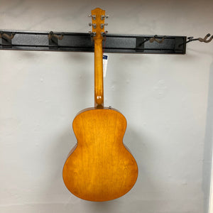 Godin 5th Avenue Jumbo P-Rail Harvest Gold guitar displayed on a wall, showcasing its archtop design and jumbo body depth.