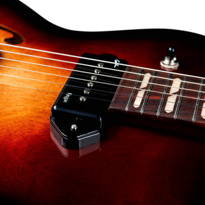 Close-up of the Godin 5th Avenue Kingpin II DLX Vintage Burst HG SF electric guitar, featuring its strings, black P90 single-coil pickup, part of the fretboard, and sunburst finish—showcasing exceptional Canadian craftsmanship.