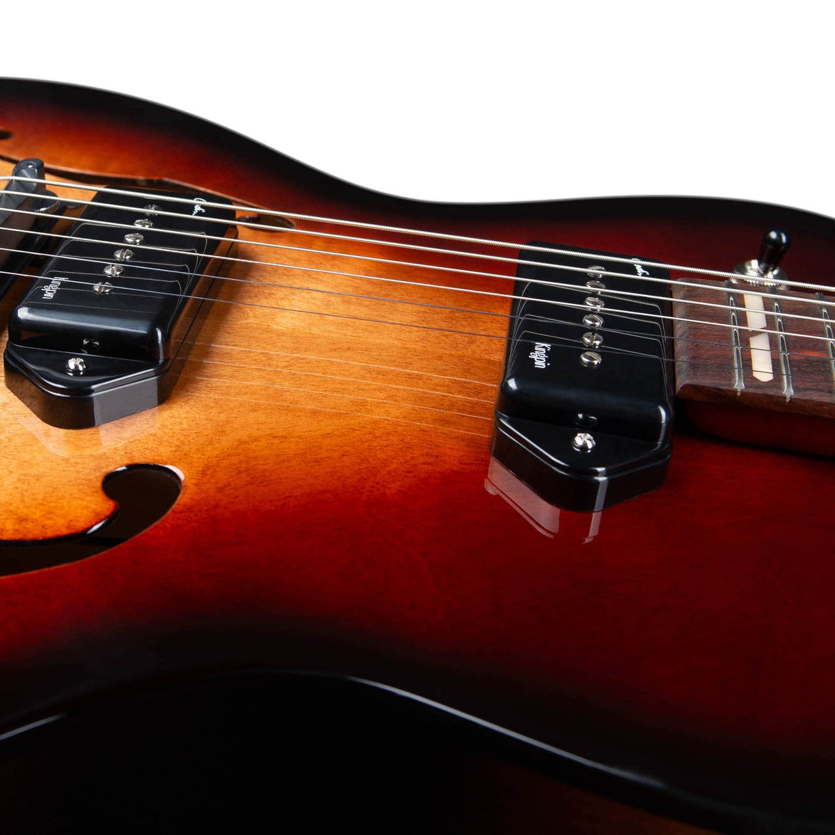 Close-up of the Godin 5th Avenue Kingpin II DLX Vintage Burst HG SF, highlighting Canadian craftsmanship with visible strings, P90 single-coil pickups, a sunburst finish, and an f-hole on the left.