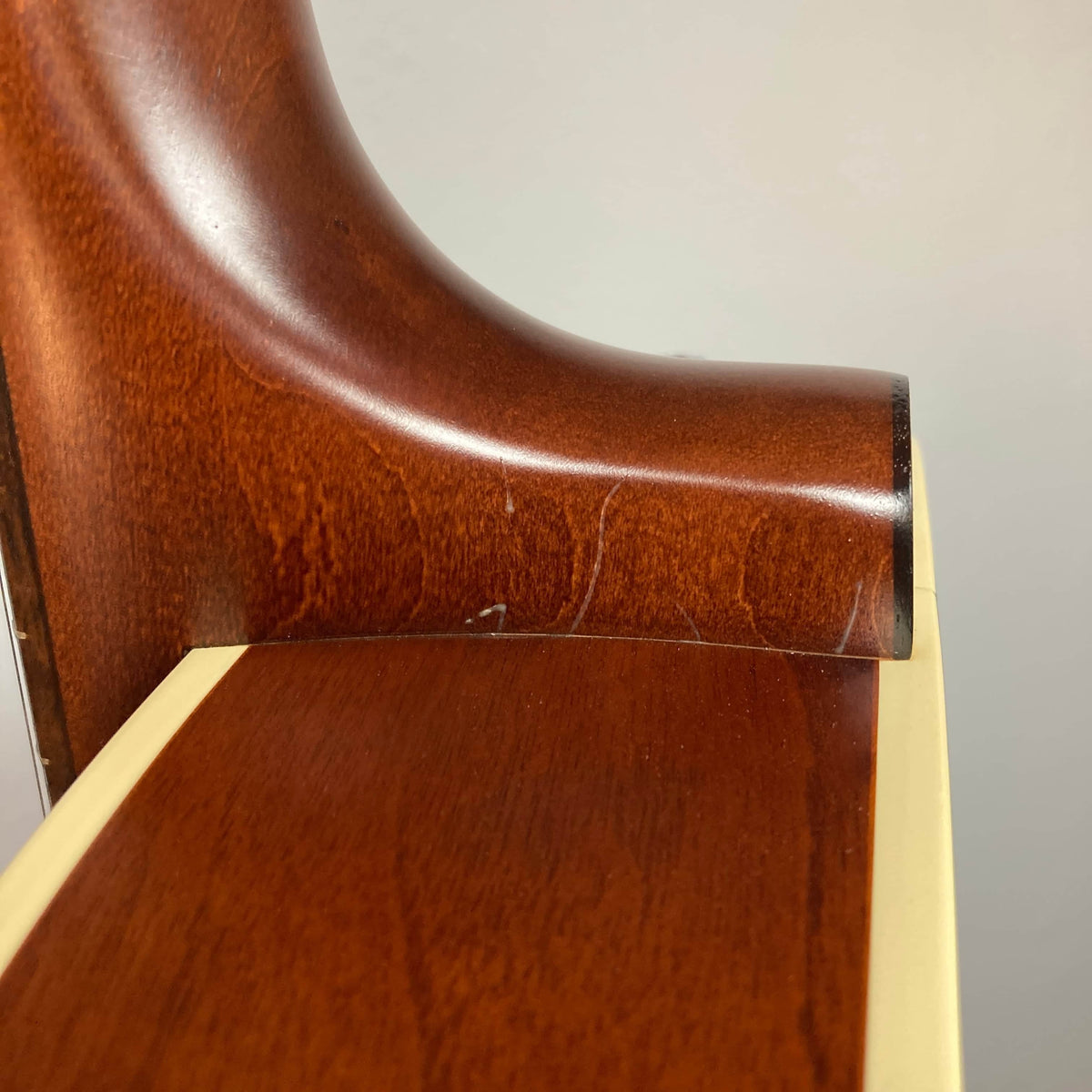 Close-up of the heel joint on the Godin 5th Avenue Kingpin P90 Cognac Burst SF, highlighting its glossy finish and rich wood grain that evoke vintage tone and a smooth neck-to-body transition.