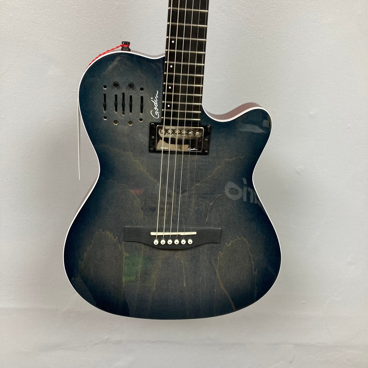 Godin A6 Ultra Denim Blue Flame SF electric guitar with Richlite bridge and fingerboard, showcasing its strings and body on a white wall.