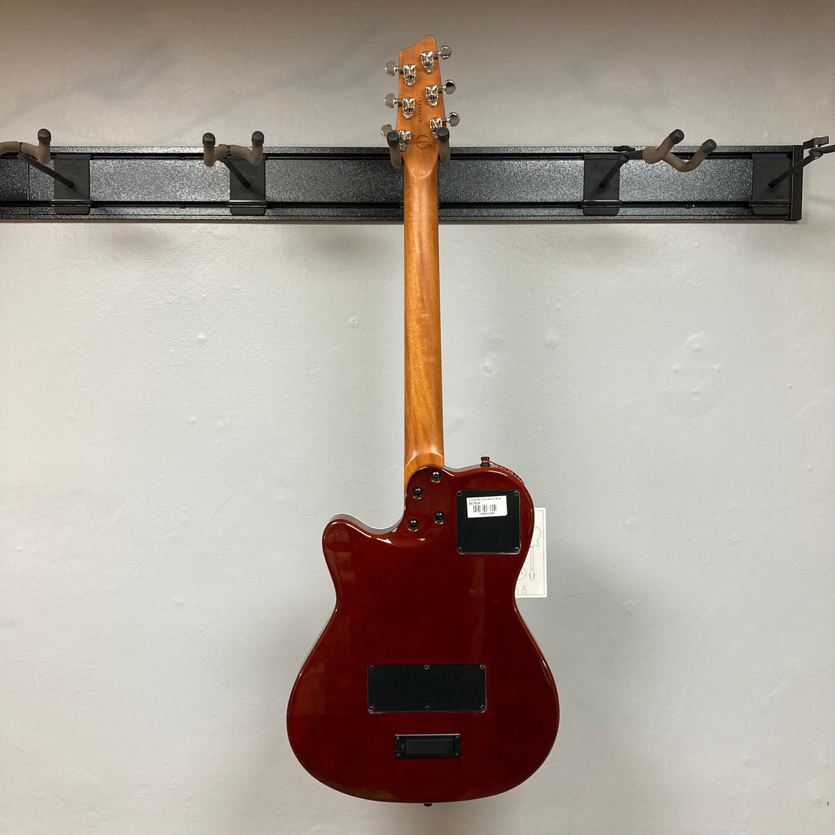 Godin A6 Ultra Denim Blue Flame SF electric-acoustic guitar on a wall, featuring a two-chambered maple body and Richlite bridge/fingerboard, displayed with a gig bag.