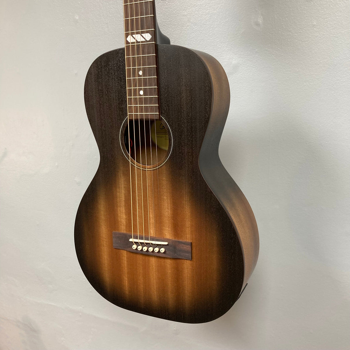 Godin Mahogany Parlor Black Burst A/E acoustic guitar with solid mahogany top and back, mounted on a wall.