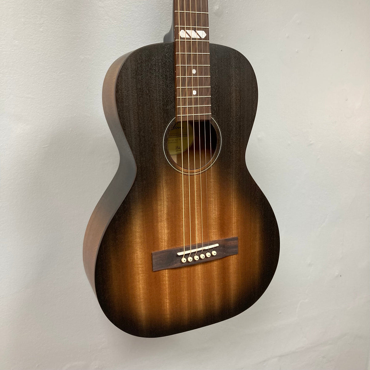 Godin Mahogany Parlor Black Burst A/E guitar with solid mahogany top and back, displayed on a wall.