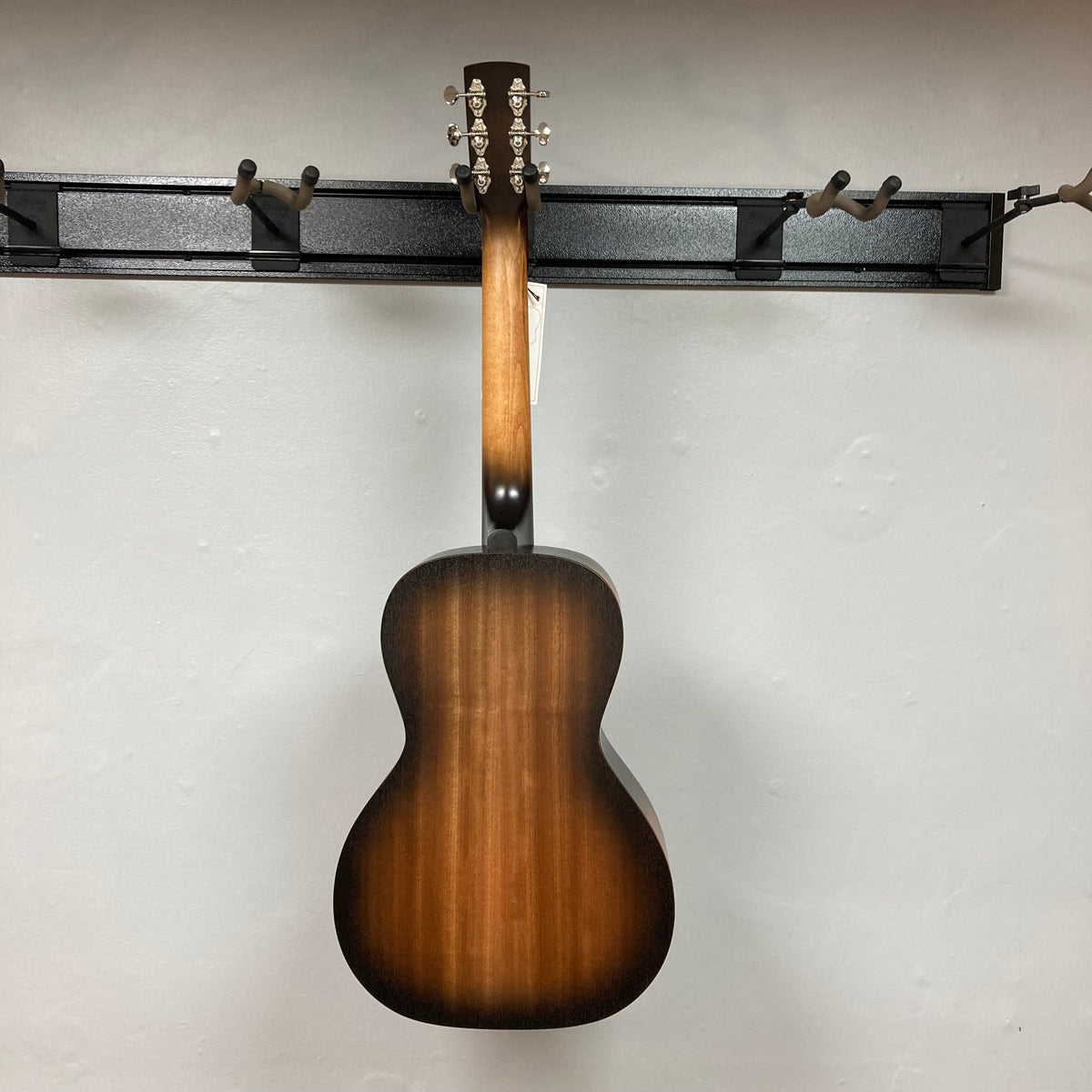 Godin Mahogany Parlor Black Burst A/E guitar displayed on a wall, showcasing its craftsmanship and design.