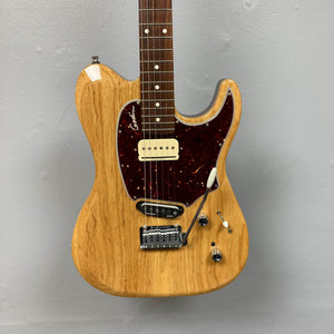Godin Passion Custom Swamp Ash Electric Guitar w/ GigBag Consign by Godin, featuring a natural wood finish, dark red pickguard, single-coil pickup, and a whammy bar, mounted against a gray wall. Offering tonal versatility inspired by instruments like the Godin Passion Custom Swamp Ash or pickups such as Seymour Duncan P-Rail, this guitar is ideal for players seeking dynamic sound options and eye-catching aesthetics.