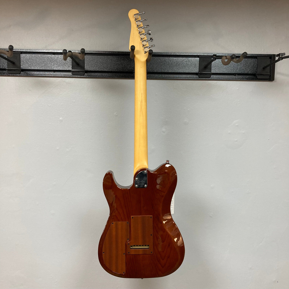 Godin Passion Custom Whiskey Burst w/Gigbag hangs on wall, showcasing its high-quality craftsmanship, detailed pickups, and innovative tremolo arm adjustment.