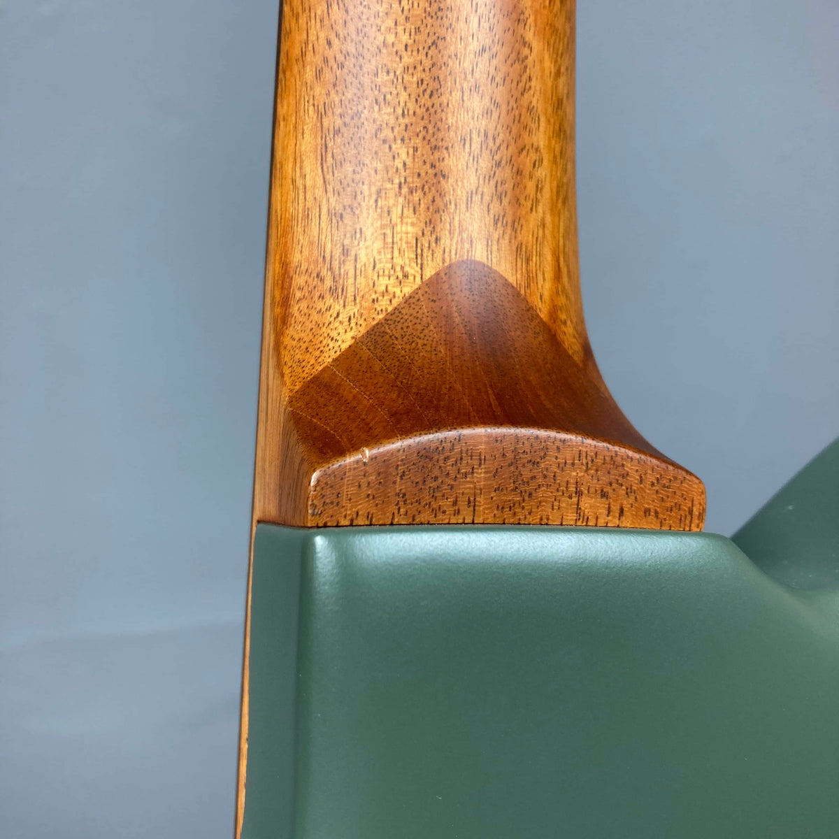Close-up of the Godin Radium Matte Green RN SF w/GigBag shows its wooden neck joint meeting the olive green body, highlighting wood grain, smooth curves, and the versatile H-S-H pickup configuration.