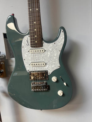 A green Godin Session T-Pro with Bag electric guitar by Godin, featuring an H-S-S pickup configuration, Seymour Duncan pickups, white pearloid pickguard, two control knobs, and a three-way switch hangs on the wall.