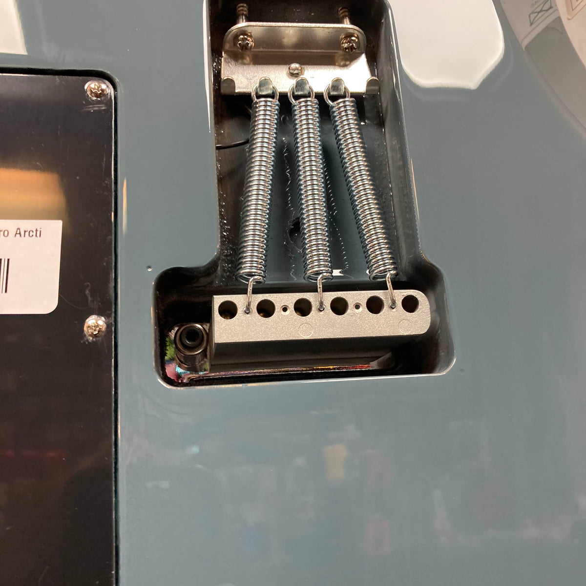 Close-up of the back of a Godin Session T-Pro with Bag by Godin, highlighting the tremolo cavity with three tension springs on the metal bridge block and part of its H-S-S pickup configuration.