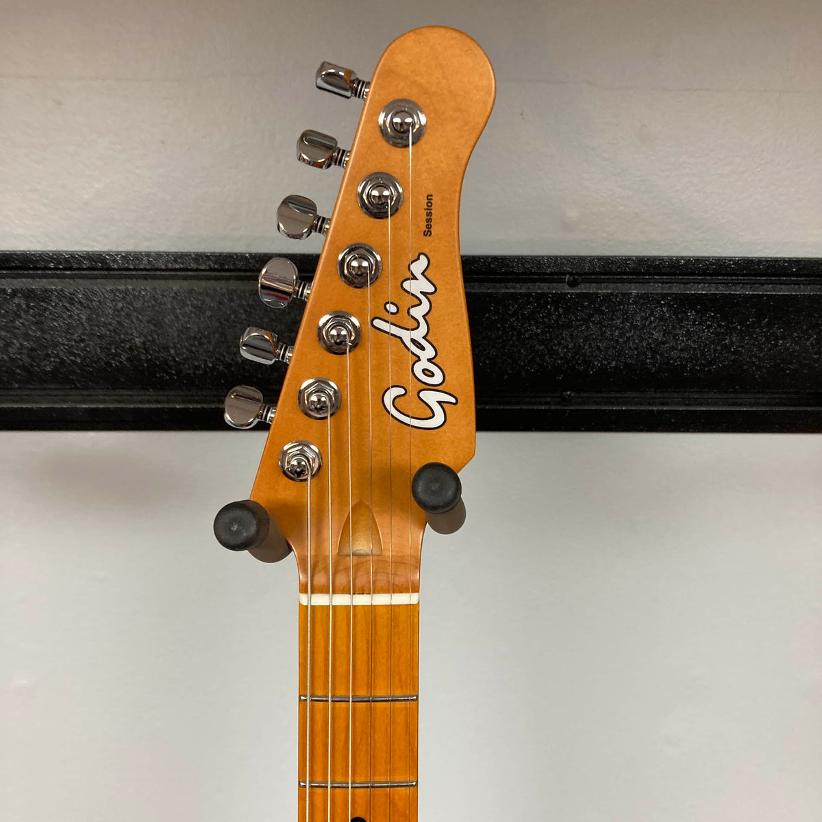Close-up of the Godin Session T-Pro with Bag headstock, displaying tuning pegs, Godin logo, and part of the fretboard against a plain background.